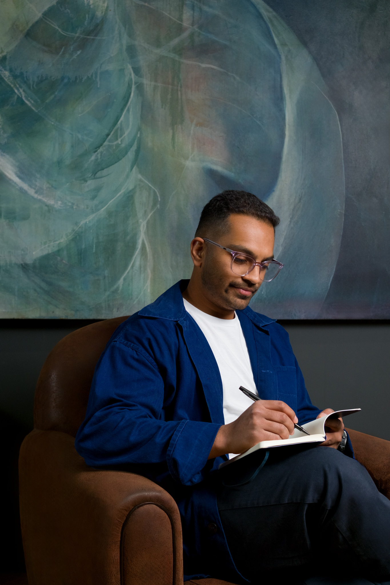 Suraj Soren, Founder and Director of Studio Soren, sketching in a notebook in a studio armchair